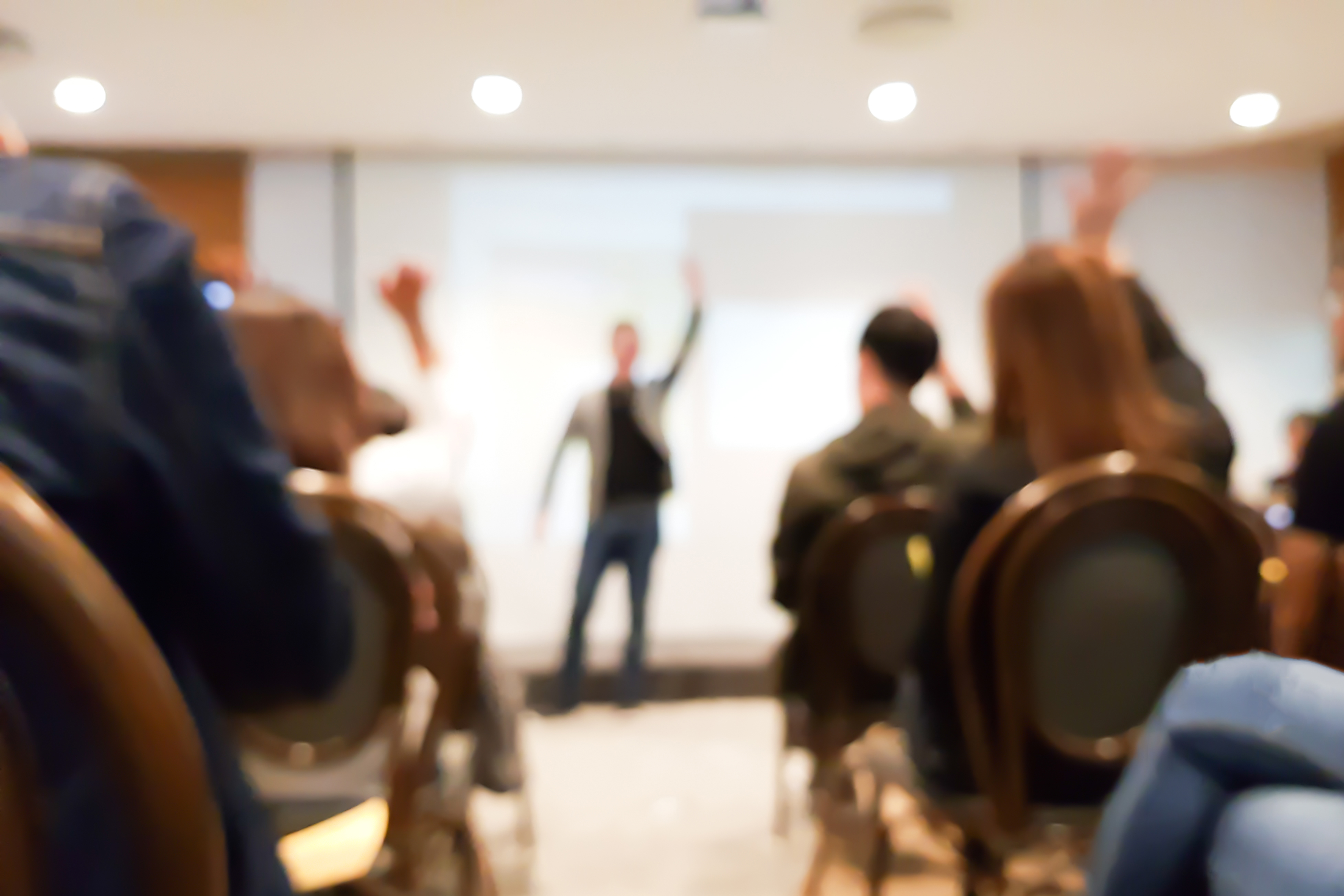 blurred group of people meeting in motivation seminar event at convention hall, speaker raising hand up and audience action follow , cheerful conceptblurred group of people meeting in motivation seminar event at convention hall, speaker raising hand up and audience action follow , cheerful concept